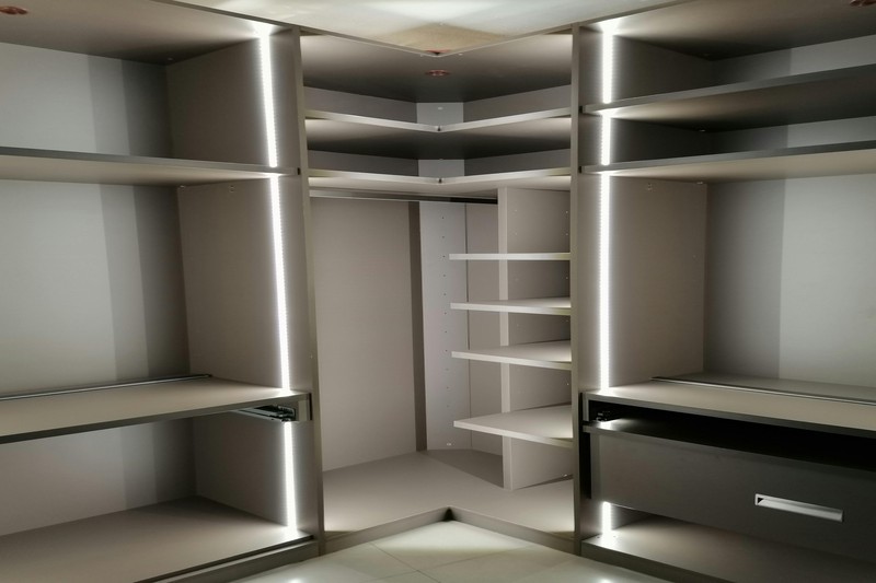 LED strip lights illuminating shelves and hanging rods in an attic walk-in closet