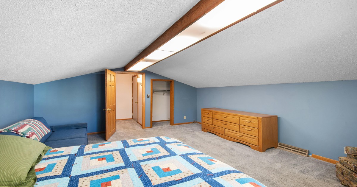 A well-organized walk-in closet in an attic with sloped ceilings, featuring custom shelving and hanging rods