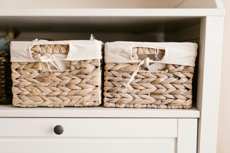Bamboo storage baskets and linen bins neatly arranged on a closet shelf in a zen closet