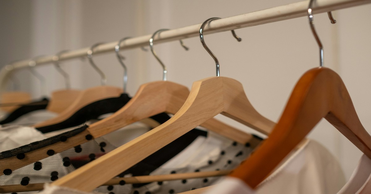 Black velvet hangers neatly arranged on a closet rod holding various garments
