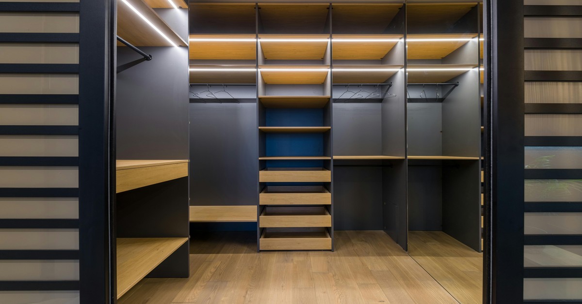 Luxurious walk-in closet with open shelving, organized handbags, and warm ambient lighting