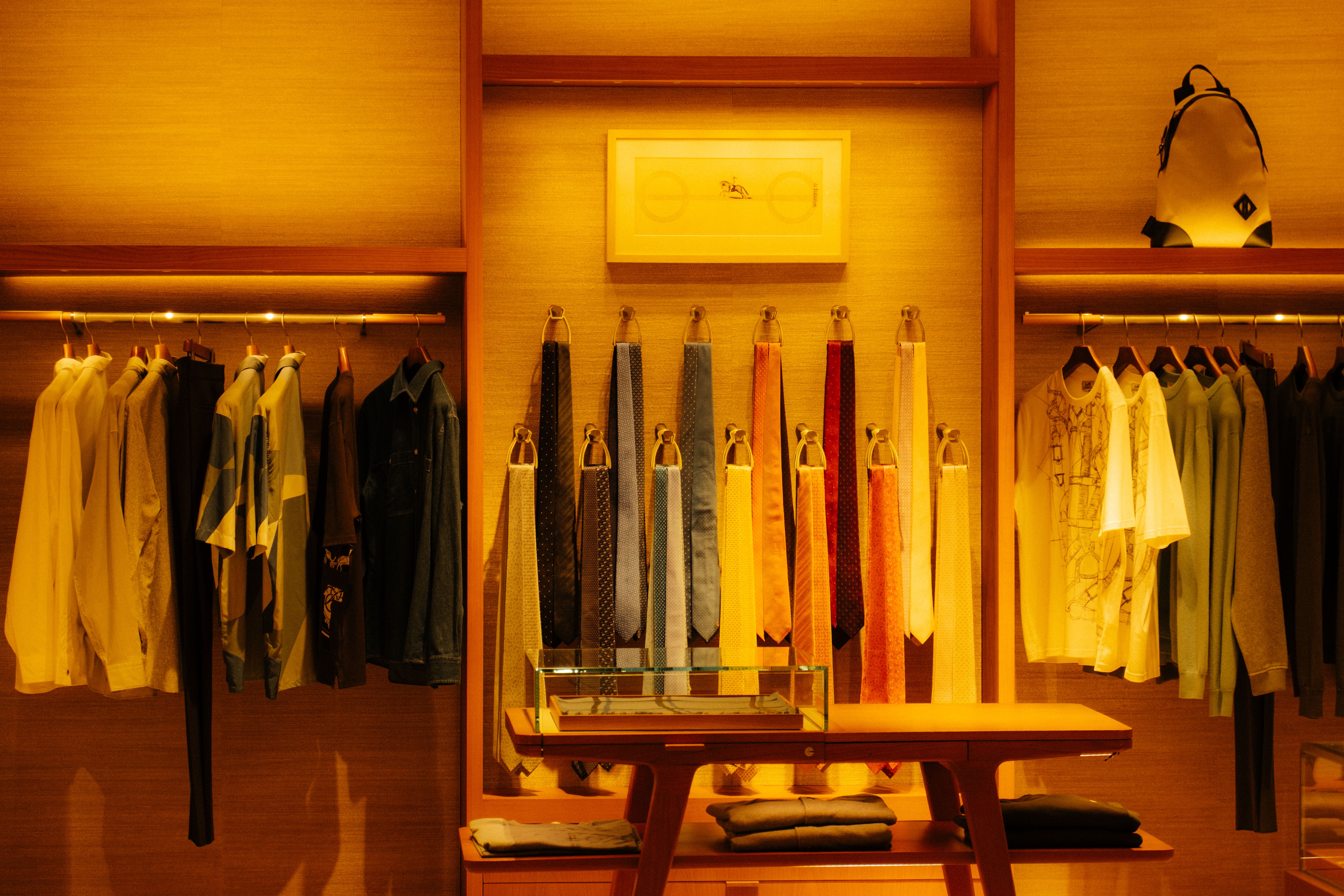 Stylish fashion store interior showcasing clothes and accessories under warm lighting.